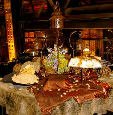 Rustic buffet display with bronze lanterns, bread baskets, and flowers