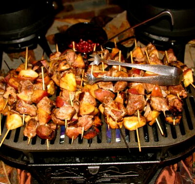 Meat-and-potato skewers cooking on a tabletop grill