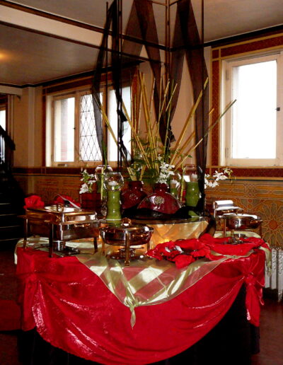 Buffet centerpiece with tall geometric panels, bamboo, white orchids, and red linens